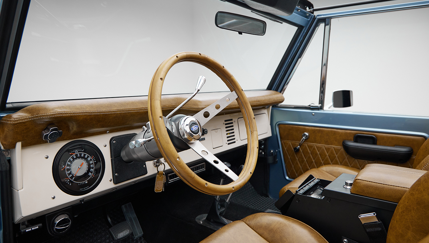 1973 Ford Bronco in Brittany Blue over Whiskey leather steering wheel
