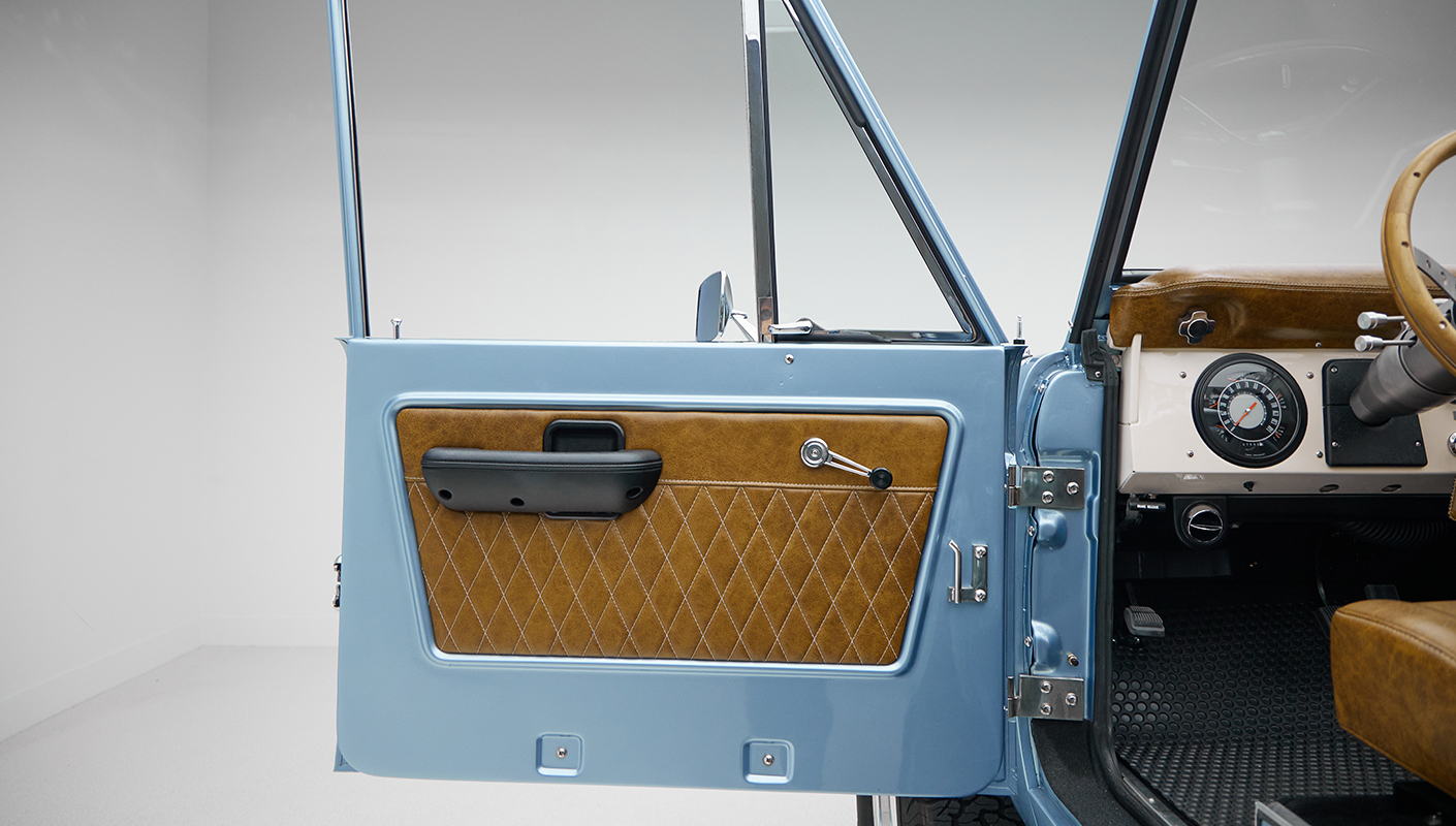 1973 Ford Bronco in Brittany Blue over Whiskey leather driver door panel