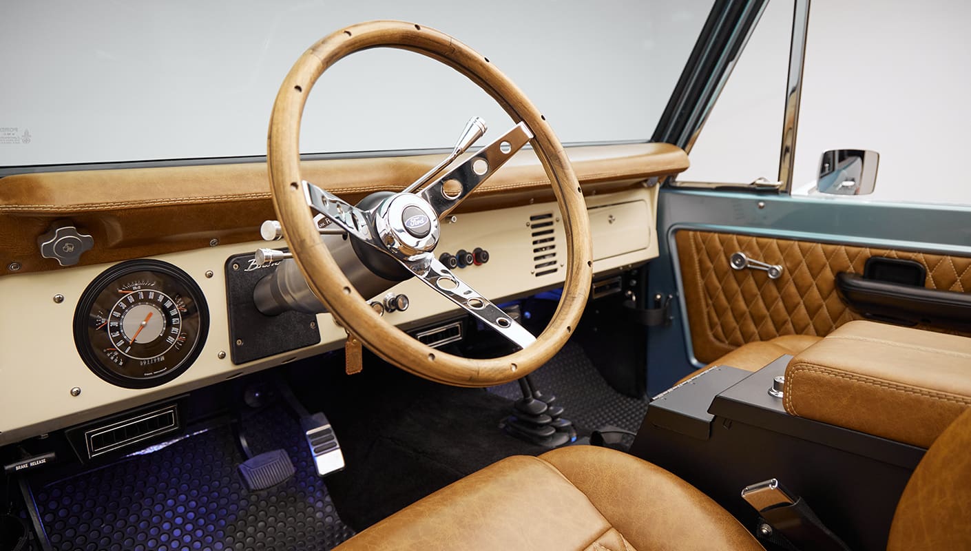1976 Ford Bronco in Brittany Blue with whiskey diamond stitch leather interior and wood grain steering wheel