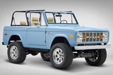 A 1976 Classic Ford Bronco is Frozen Blue over White Rock leather passenger front 3/4