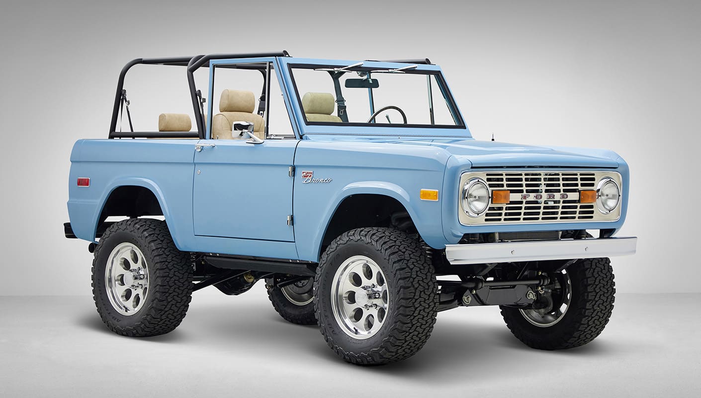 A 1976 Classic Ford Bronco is Frozen Blue over White Rock leather passenger front 3/4