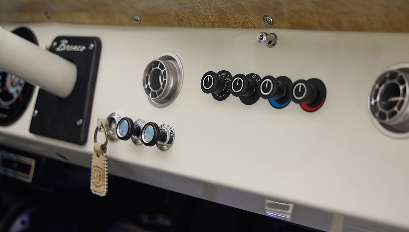 A 1976 Classic Ford Bronco is Frozen Blue over White Rock leather dash knobs