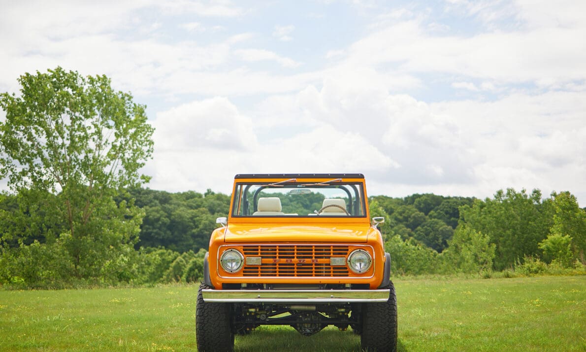 A 1969 Classic Ford Bronco named “Churchill Downs” is parked on an open grassy field under a bright sky, showcasing its lifted stance, open cabin, and premium restoration details. Built by Classic Ford Broncos, this vintage SUV represents expert craftsmanship, timeless style, and a blend of classic heritage with modern performance.